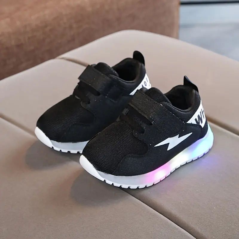 Een vrolijk kind draagt comfortabele GlowSteps peuter LED sneakers tijdens het buitenspelen op gras.