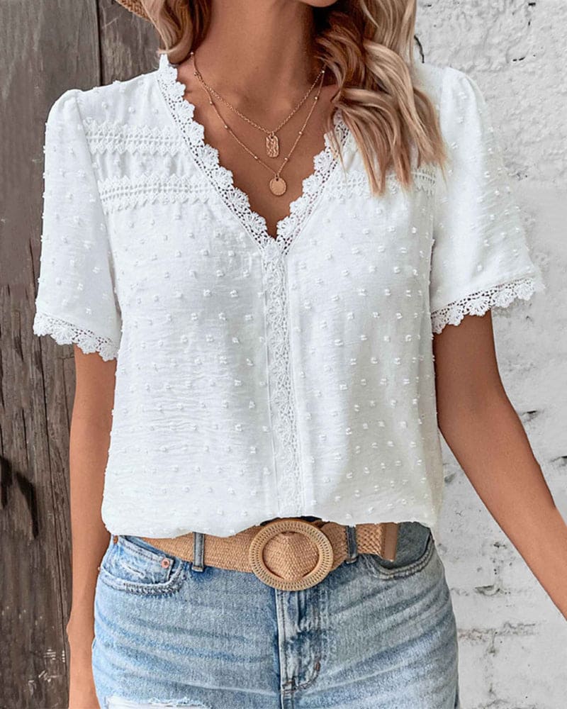 Close-up van dames kanten zomerblouse met delicate details, korte mouwen en stijlvolle V-hals.