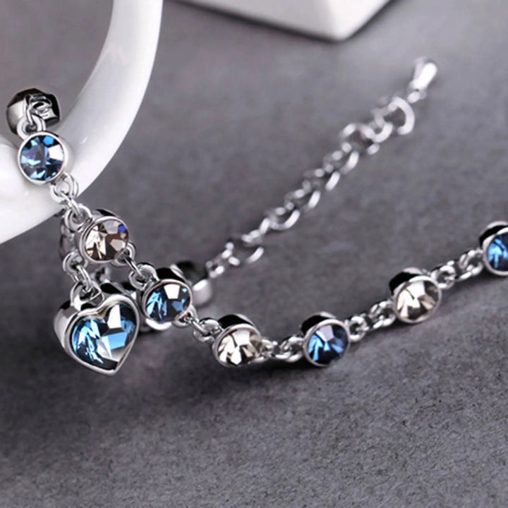 Glinsterende damesarmband van kristal en zirkonia met een blauwe hartbedel. Elegant verstelbaar sieraad.