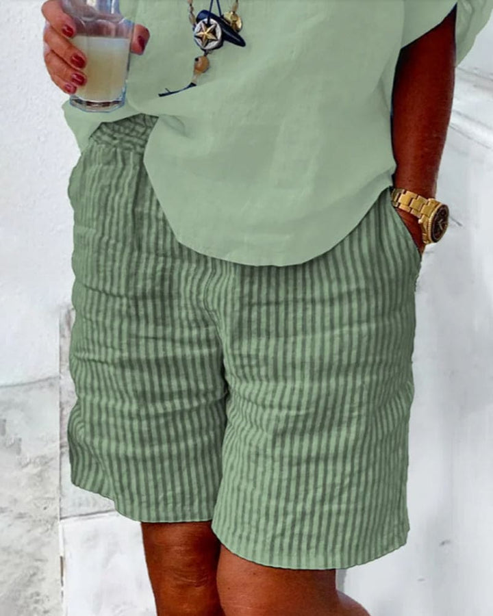 Vrouw draagt trendy gestreepte damesshorts met middelhoge taille, ideaal voor strand of stad.