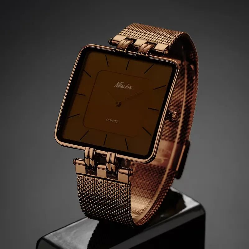 Formeel heren analoog horloge, goudkleurig, vierkante wijzerplaat met bijpassende koffiekleurige meshband. Een tijdloos accessoire.