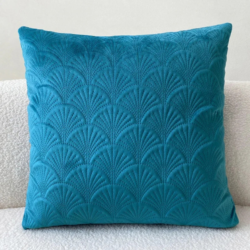 Close-up van de textuurrijke fluwelen kussenhoes, accentuerend het decoratieve schelppatroon.