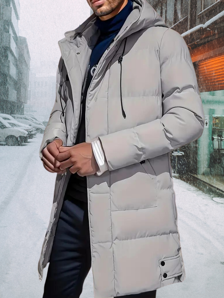 Man draagt een modieuze lange zwarte puffer winterjas met capuchon; perfect voor koude dagen.
