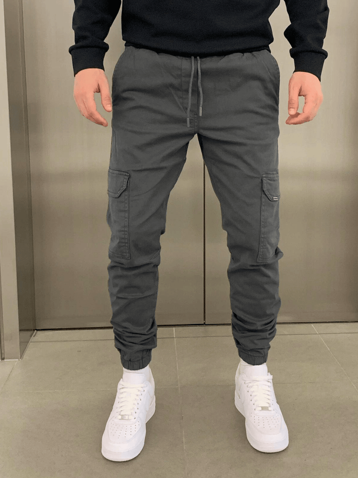Close-up van de stevige stof en de praktische cargozak van deze heren jogger broek.
