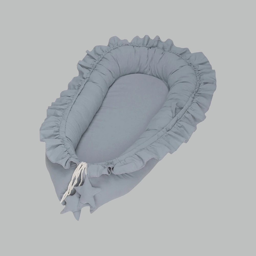 Draagbaar babynestje in zacht grijs katoen, perfect voor comfortabele slaap overal. Beschikbaar in roze, blauw, beige.