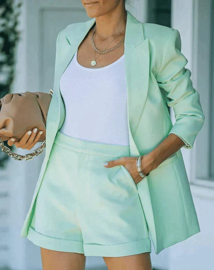 Vrouw draagt een modieuze SANDSBERGORIGINALS gekleurde blazer en korte broek set, perfect voor de zomer.